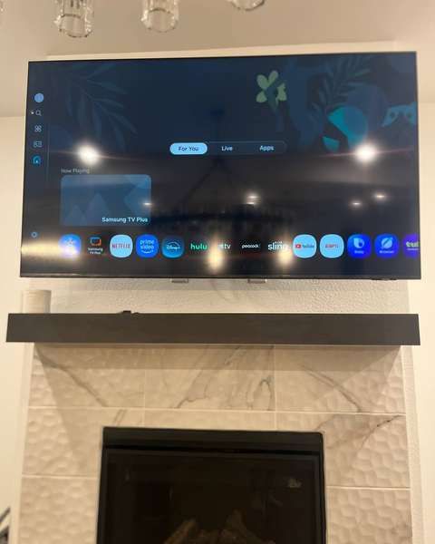 TV above a tiled fireplace with a wood mantel